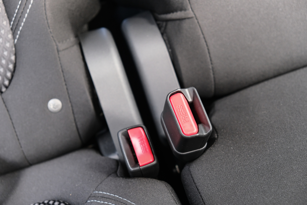 Car seat belt buckles on rear seat showing red release buttons after a collision
